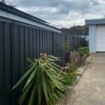 Fence with plants along the side of a property.